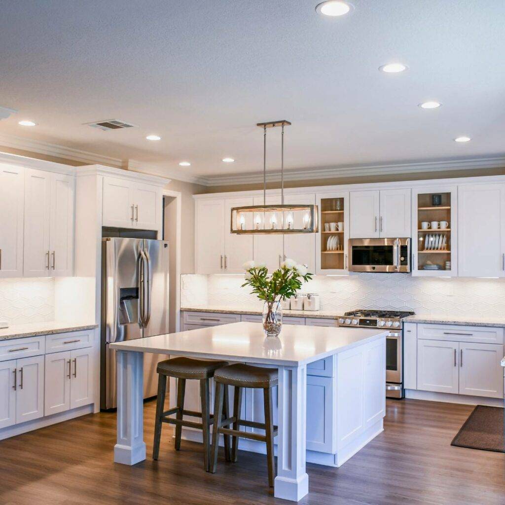 white kitchen cabinets and countertops with hanging light fixture above island counter
