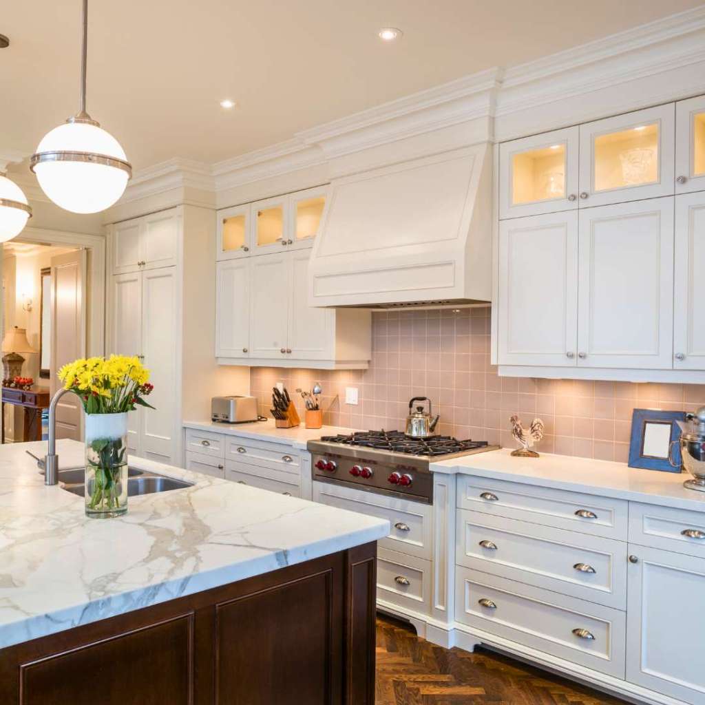 residential kitchen with white cabinets and pink backsplash